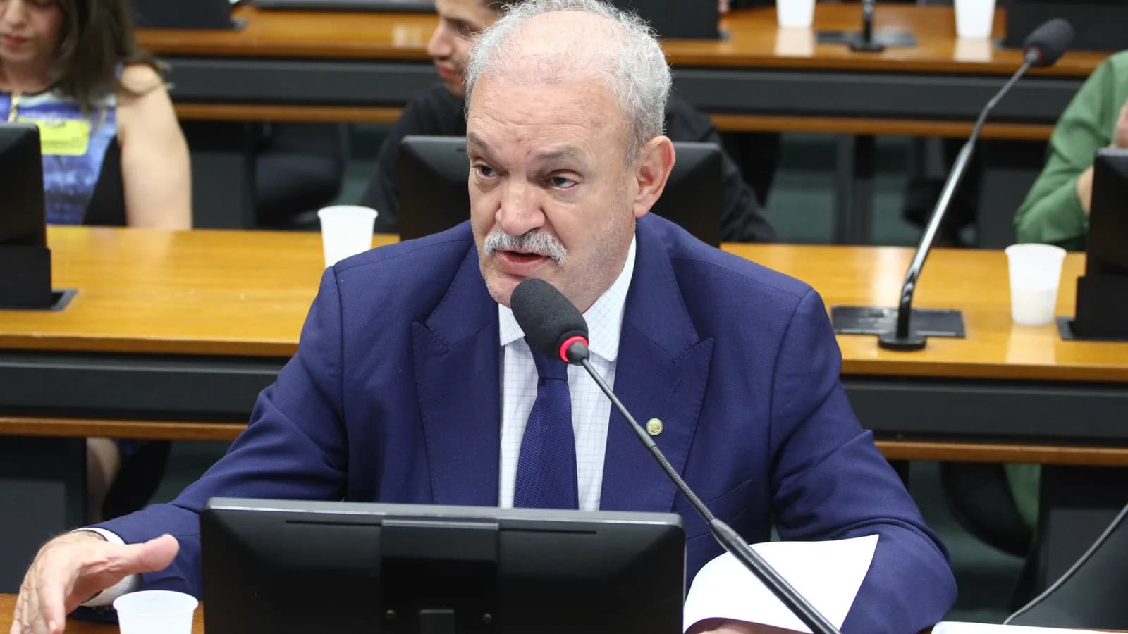 Deputado fala ao microfone em audiência pública sobre critérios de avaliação biopsicossocial em concursos públicos, na Câmara dos Deputados