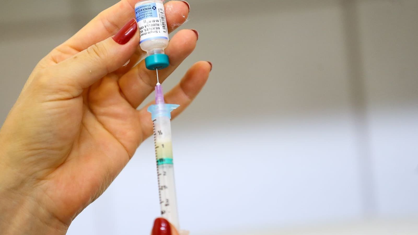 Mão de profissional de saúde aspira com uma seringa a dose de um frasco da vacina tríplice viral, contra sarampo, caxumba e rubéola, em imagem de arquivo