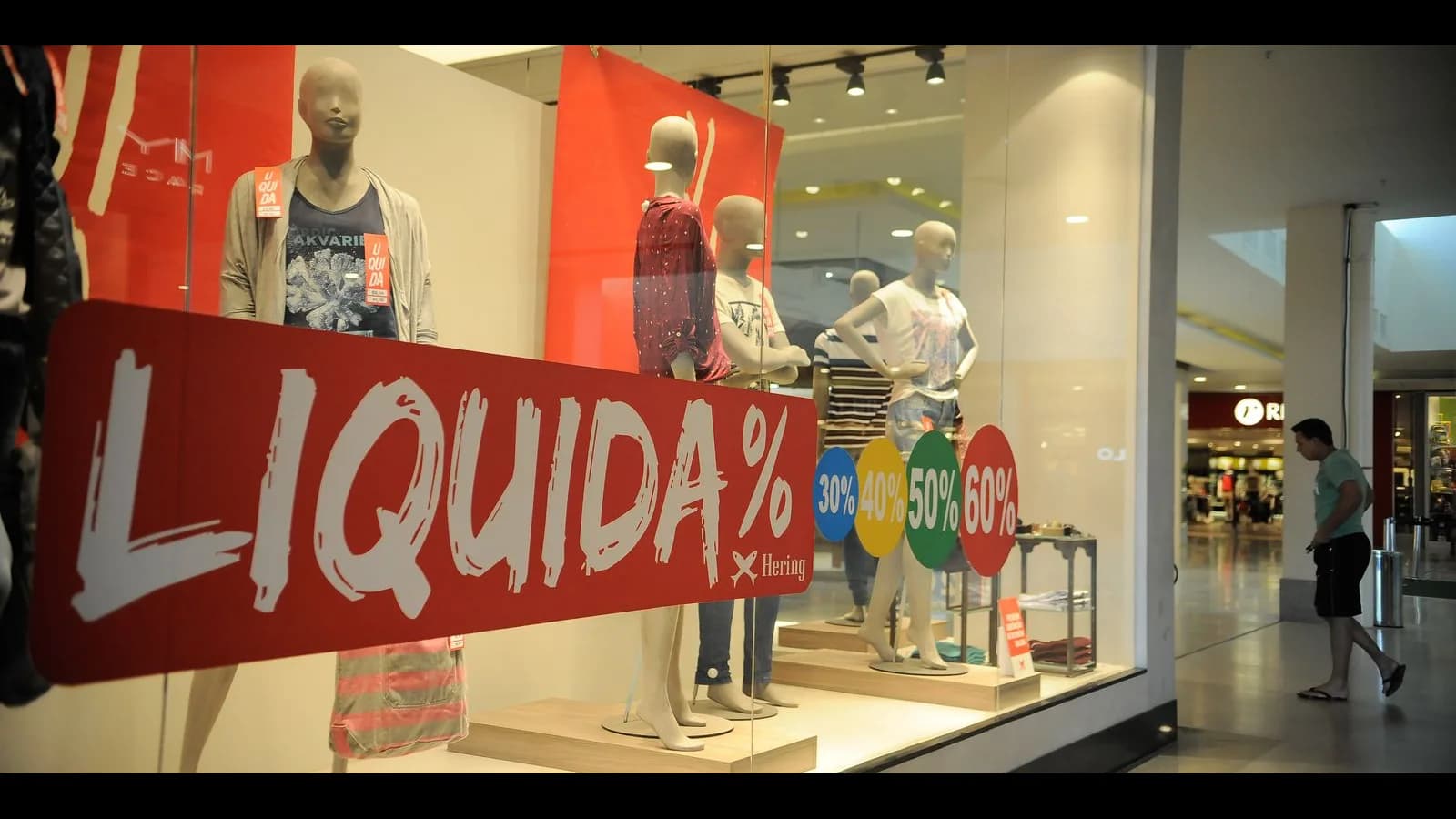 Vitrine de loja em shopping com cartazes de liquidação e promoção de descontos