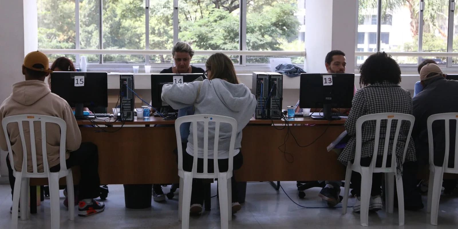 Pessoas sentadas em guichês de atendimento durante mutirão de renegociação de dívidas (foto ilustrativa, arquivo)