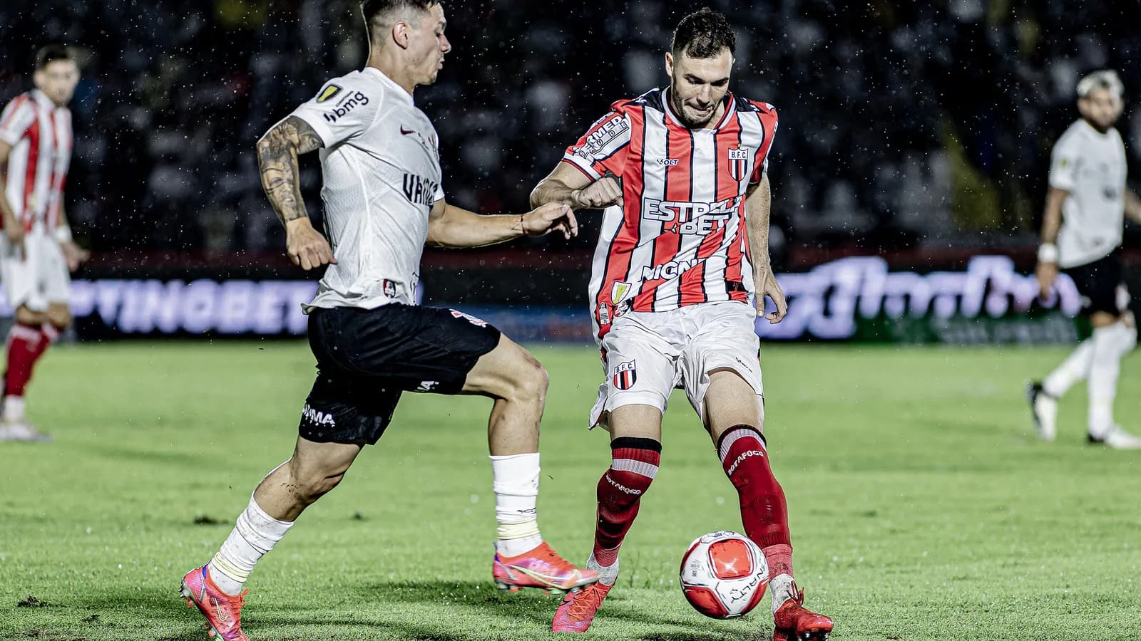 Jogador do Botafogo-SP disputa a bola com adversário do Corinthians em campo (foto de arquivo)