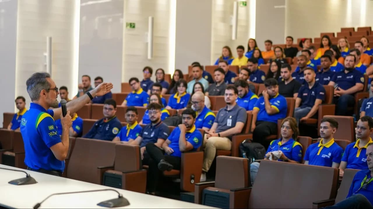 Delegação brasileira reunida em auditório antes da WorldSkills Shanghai 2026, jovens de uniforme azul do Team Brasil ouvindo instrutor