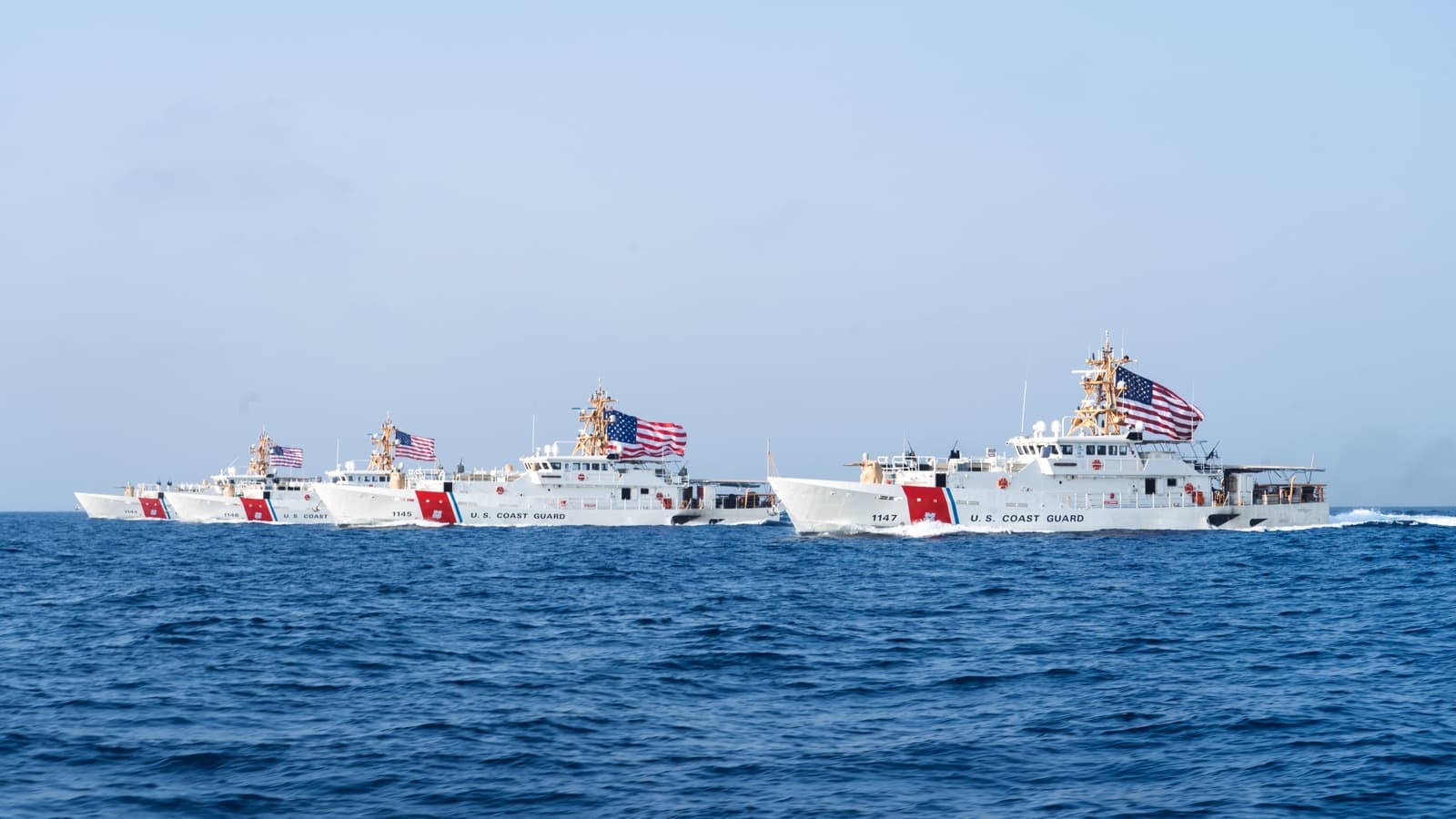 Quatro navios de patrulha da Guarda Costeira dos Estados Unidos navegam em fila pelo Estreito de Ormuz, com bandeiras americanas hasteadas, em imagem de arquivo de agosto de 2022