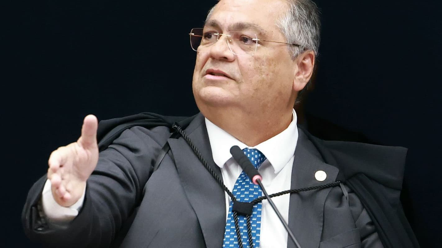 Ministro Flávio Dino, do STF, gesticula durante sessão, vestindo toga e usando óculos