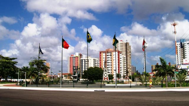 Vista da entrada da cidade de Fortaleza, no Ceará, com prédios e bandeiras ao fundo
