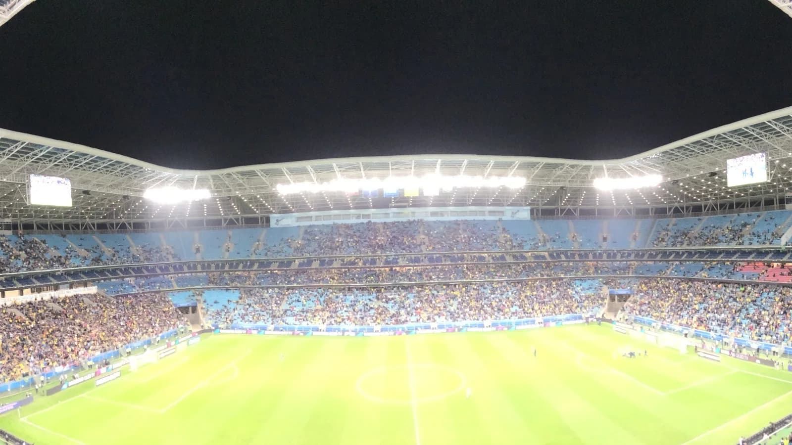 Vista panorâmica da Arena do Grêmio lotada durante uma partida noturna