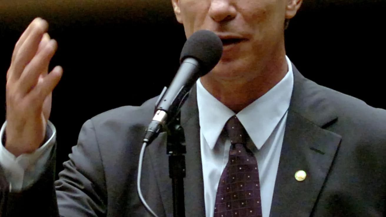 Ciro Gomes discursando em microfone, terno escuro, gesticulando