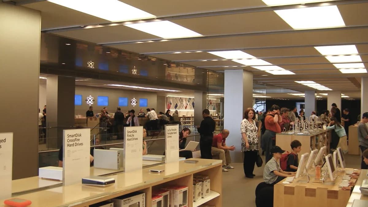 Interior de uma loja da Apple com clientes analisando produtos em mesas de exposição