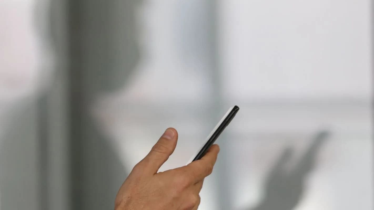 Mão segura celular ao acessar aplicativo, em imagem de contexto sobre apostas online