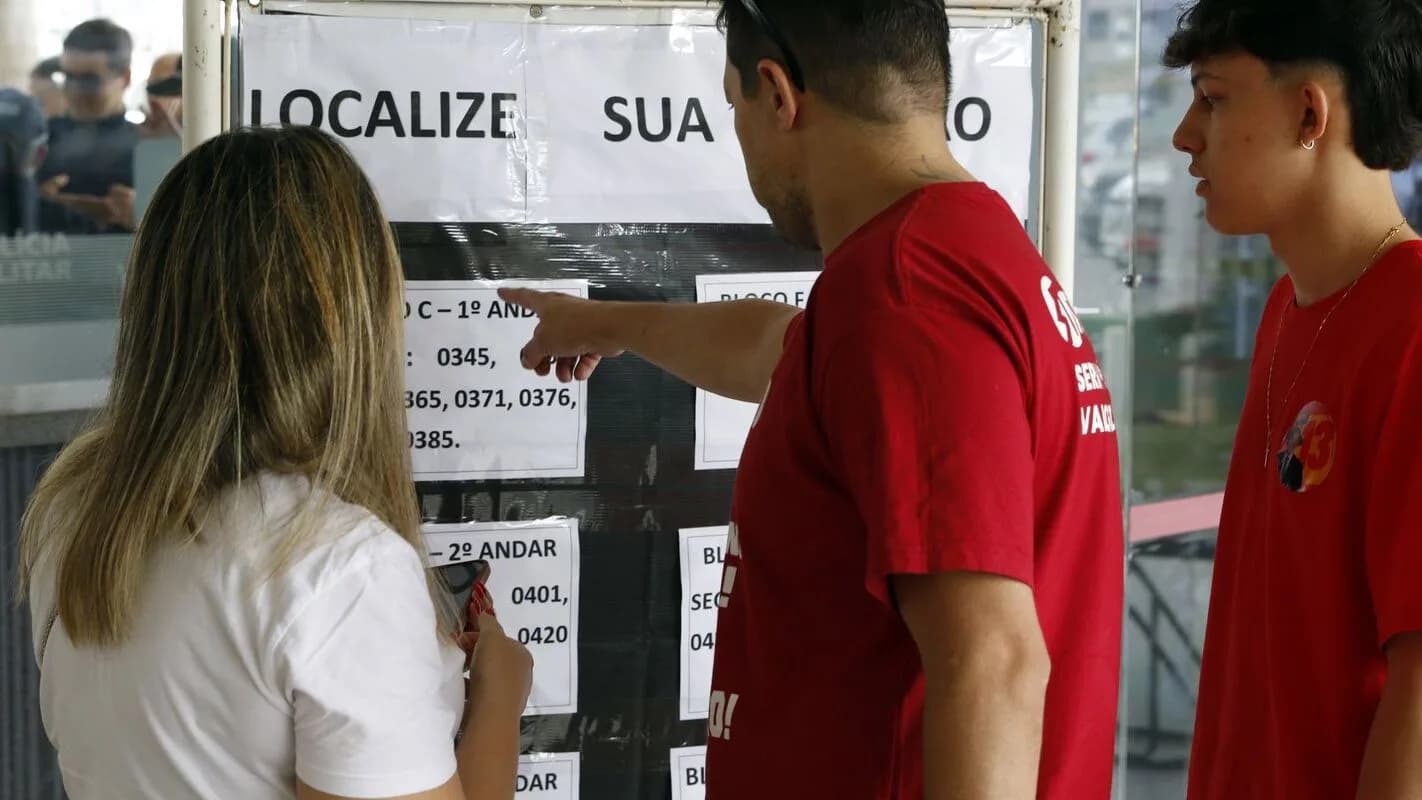Eleitores conferem lista de locais de votação em mural de prédio público