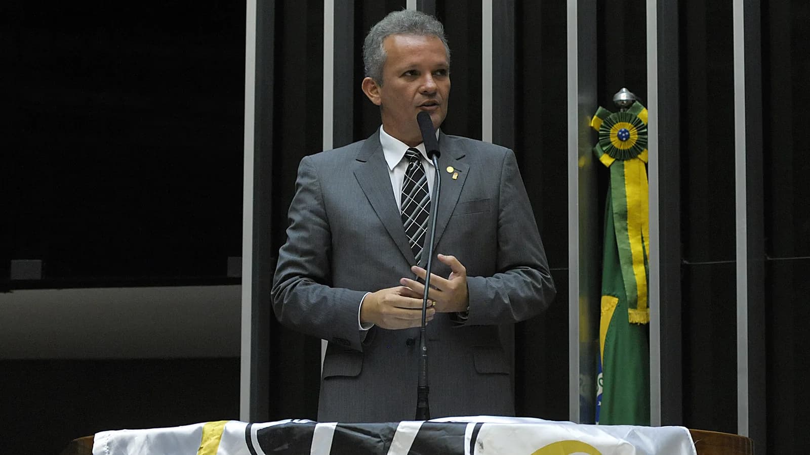 Deputado discursa em homenagem ao centenário do Ceará Sporting Club, com bandeira do clube ao fundo