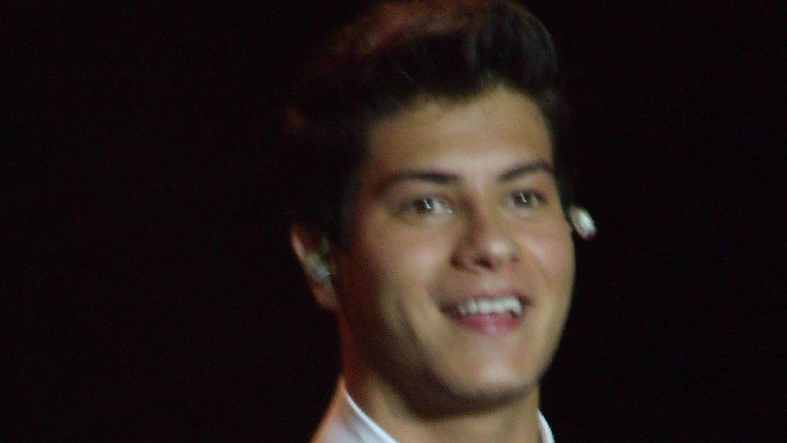 Arthur Aguiar sorri durante apresentação em show, com microfone na mão e ponto eletrônico no ouvido