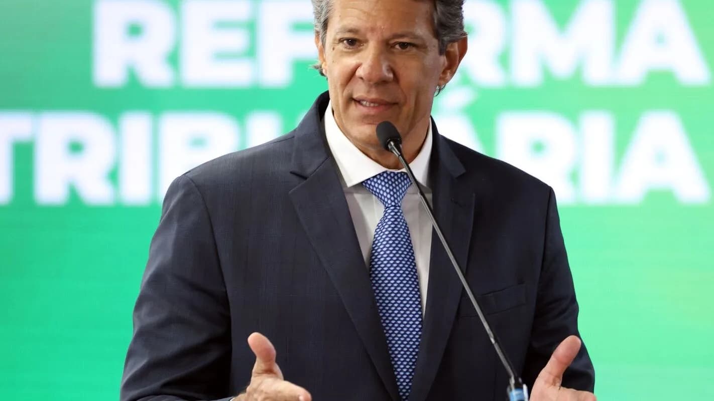 O ministro da Fazenda, Fernando Haddad, discursa com painel da Reforma Tributária ao fundo