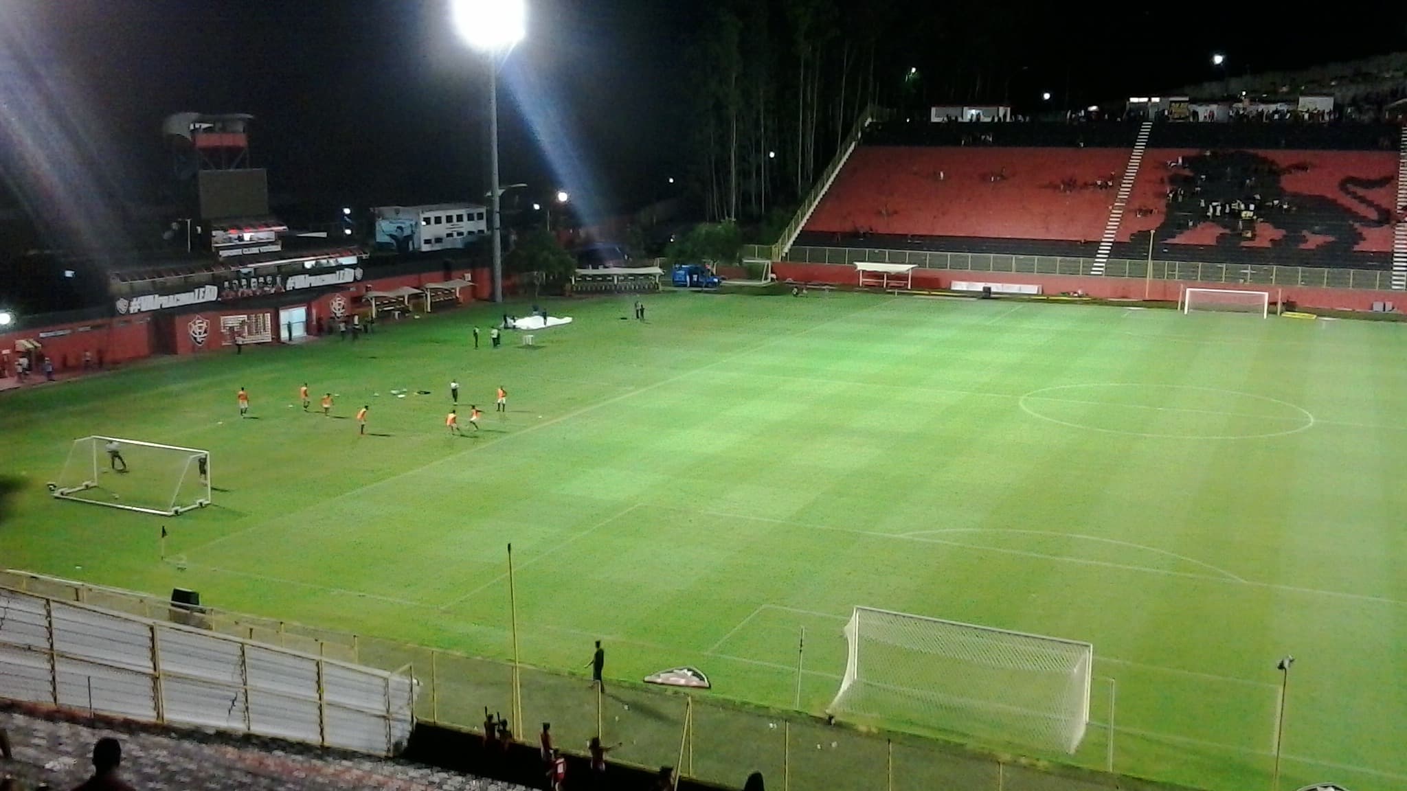 Foto de arquivo do Estádio Barradão à noite, com jogadores do Vitória em aquecimento antes de partida