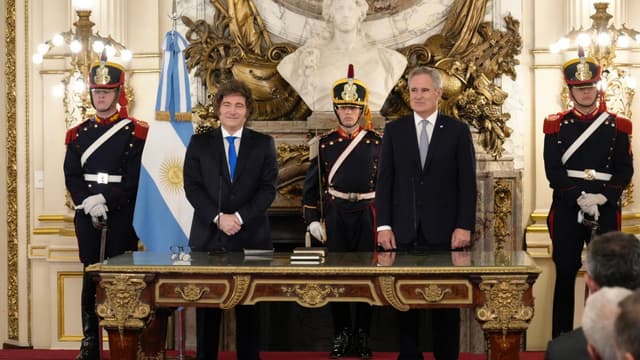 Presidente argentino Javier Milei, à esquerda, e o chanceler Pablo Quirno, à direita, de pé atrás de uma mesa na cerimônia de posse de Quirno, ladeados por granadeiros e pela bandeira da Argentina; foto de arquivo