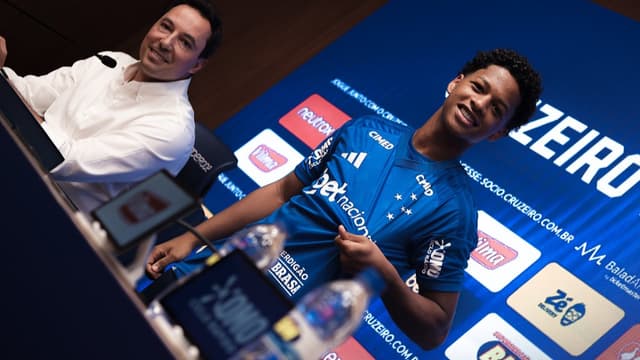 Zé Lucas sorri ao lado de dirigente do Cruzeiro durante apresentação na Toca da Raposa II