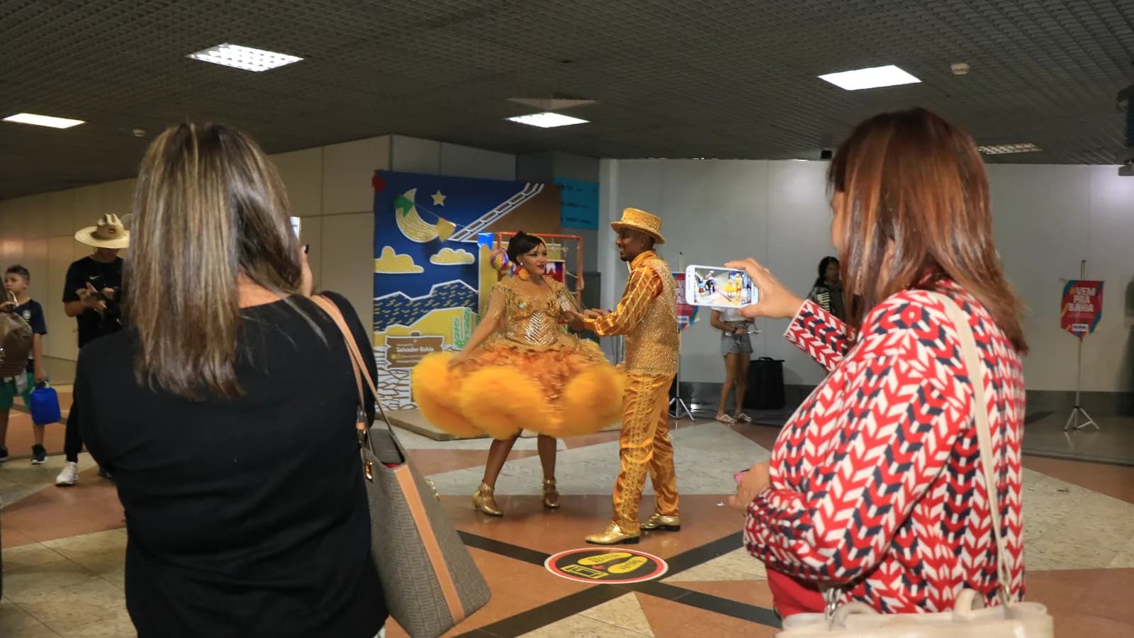 Turistas são fotografados por dançarinos folclóricos em aeroporto brasileiro