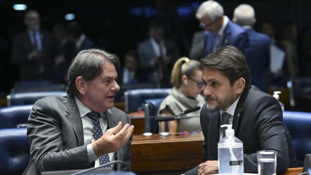 Dois senadores conversam entre as bancadas durante sessão no Plenário do Senado Federal