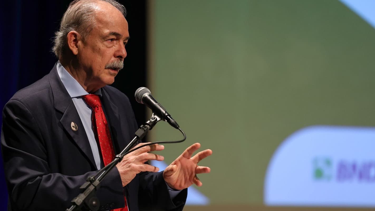 Aloizio Mercadante, presidente do BNDES, discursa em coletiva de imprensa em São Paulo, com o logotipo do banco ao fundo