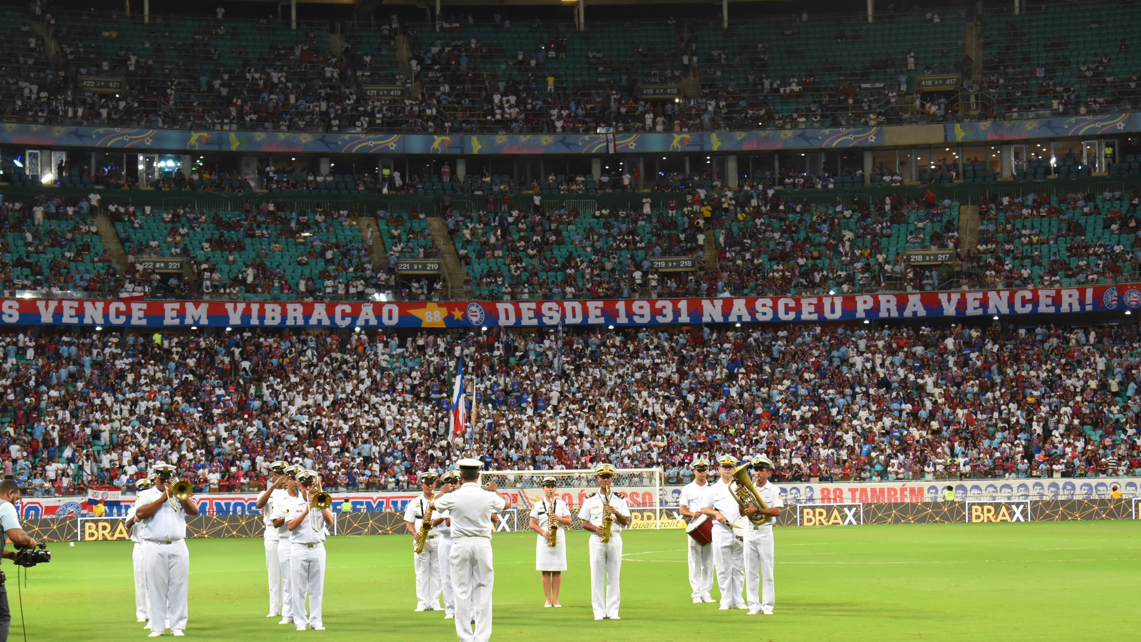 Arena Fonte Nova lotada por torcedores do Bahia, com banda da Marinha se apresentando no gramado antes de um jogo, em imagem de arquivo