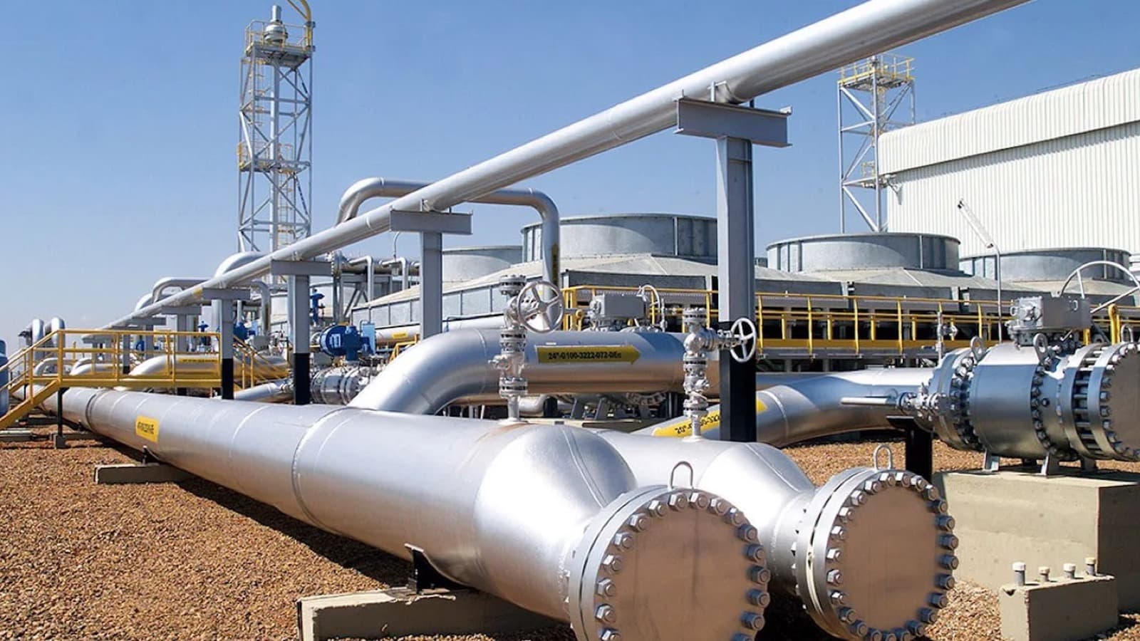 Estação de gasoduto com tubulações de aço e válvulas industriais sob céu azul, em imagem de arquivo