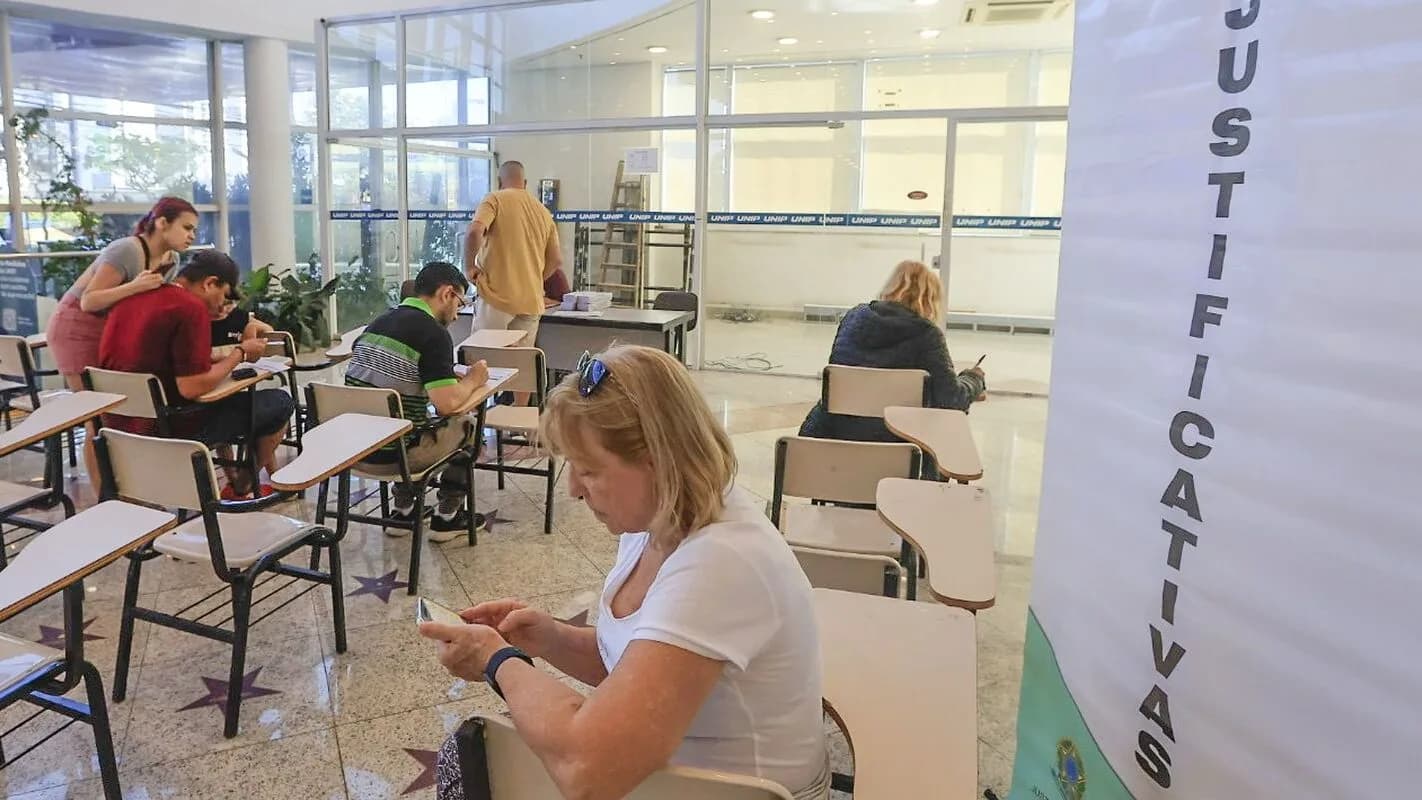 Eleitores preenchem formulário de justificativa eleitoral em posto da Justiça Eleitoral
