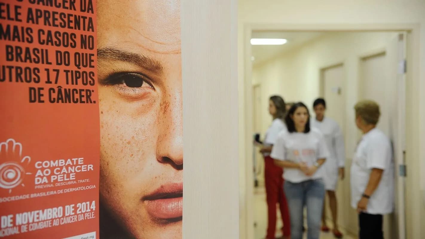 Cartaz de campanha de combate ao câncer de pele e profissionais de saúde em corredor de hospital (foto de arquivo, ilustrativa)