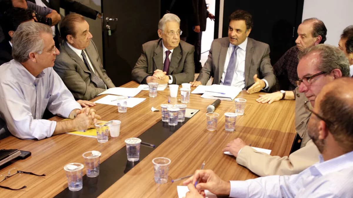 Aécio Neves em reunião de comitê político, cercado por outras lideranças à mesa
