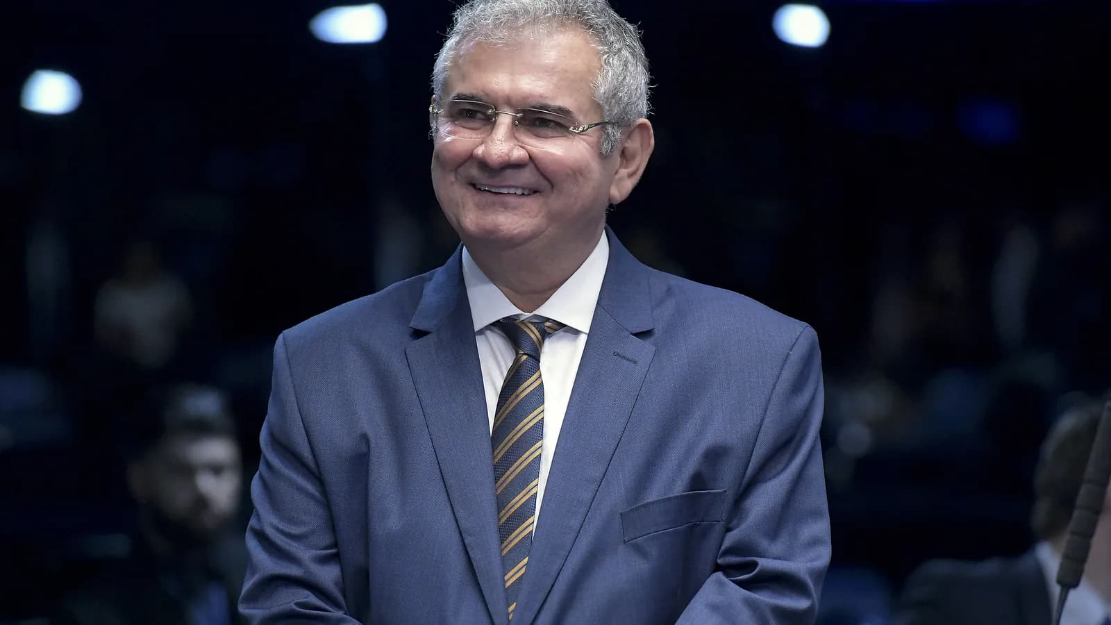 Senador Angelo Coronel sorri em terno no plenário do Senado
