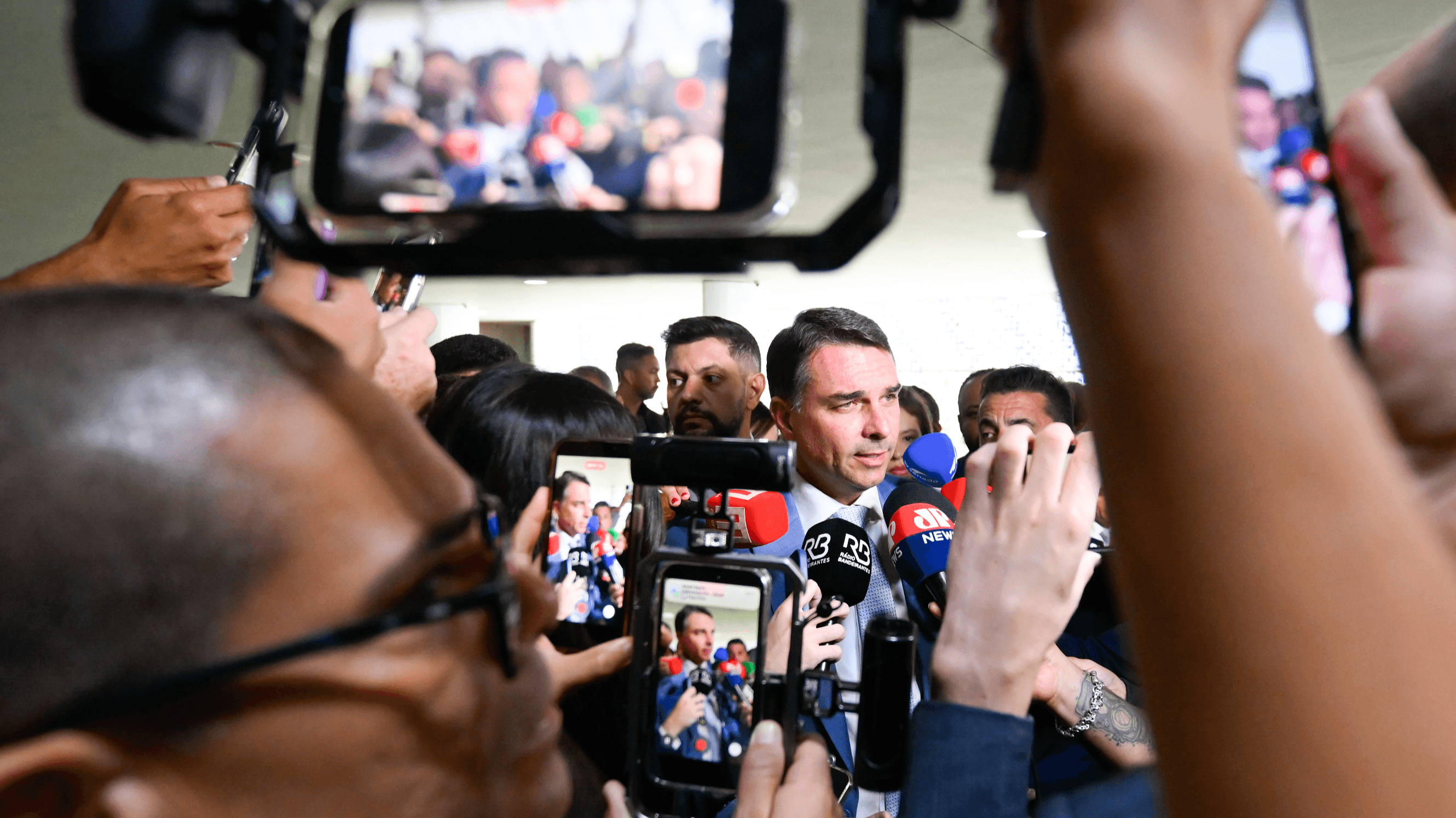 Senador Flávio Bolsonaro cercado por microfones e celulares concede entrevista a jornalistas