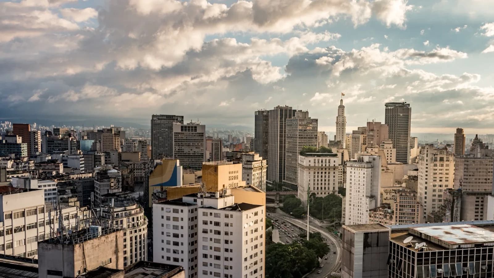 Vista aérea de prédios comerciais e residenciais no centro de São Paulo, com nuvens ao fundo