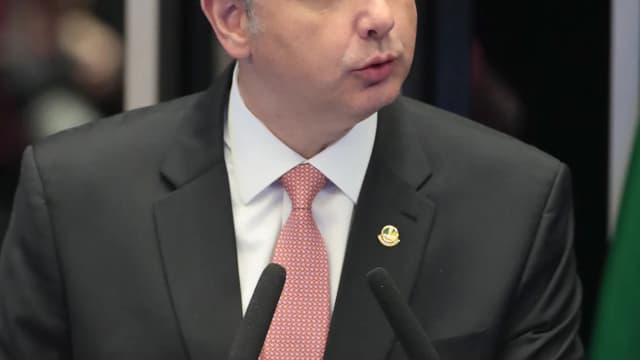 Rodrigo Pacheco discursa em podium com a bandeira do Brasil ao fundo