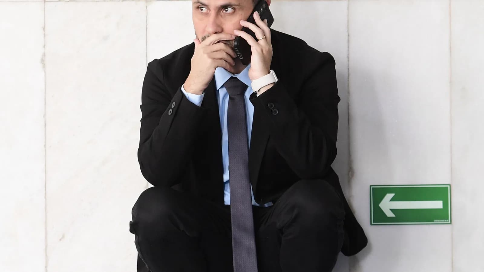 Cleitinho Azevedo fala ao telefone agachado em corredor do Senado Federal