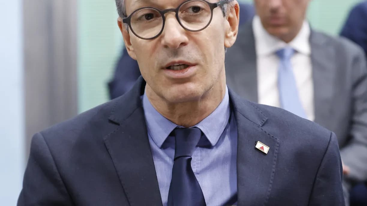 Romeu Zema, de terno e óculos, fala em reunião com outras pessoas ao fundo