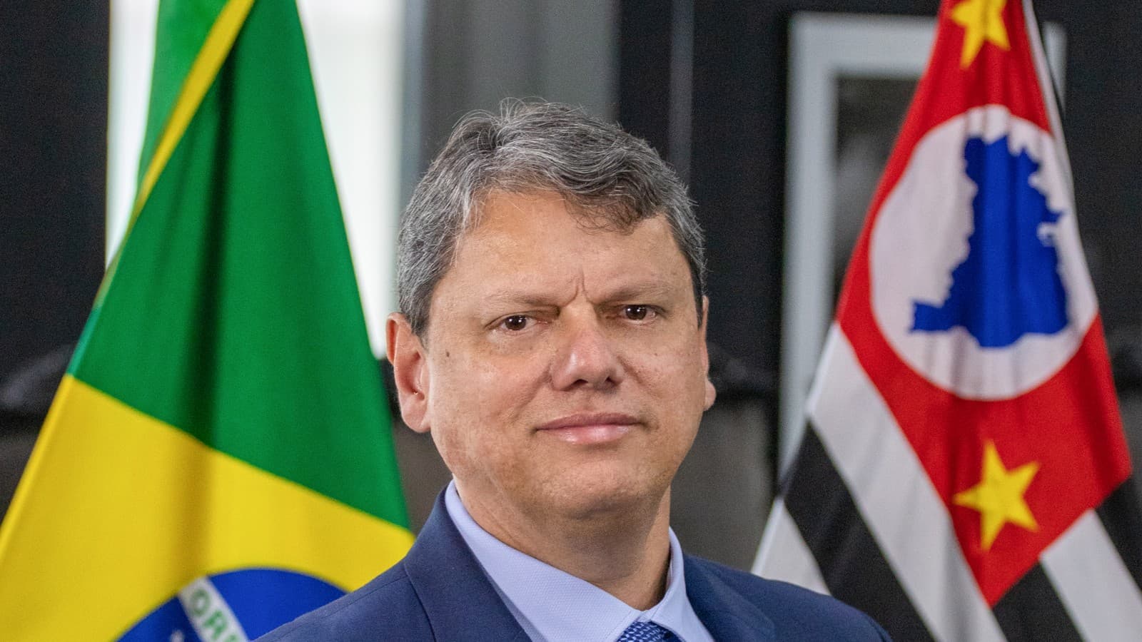 Tarcísio de Freitas, governador de São Paulo, em retrato oficial com bandeiras do Brasil e de São Paulo ao fundo