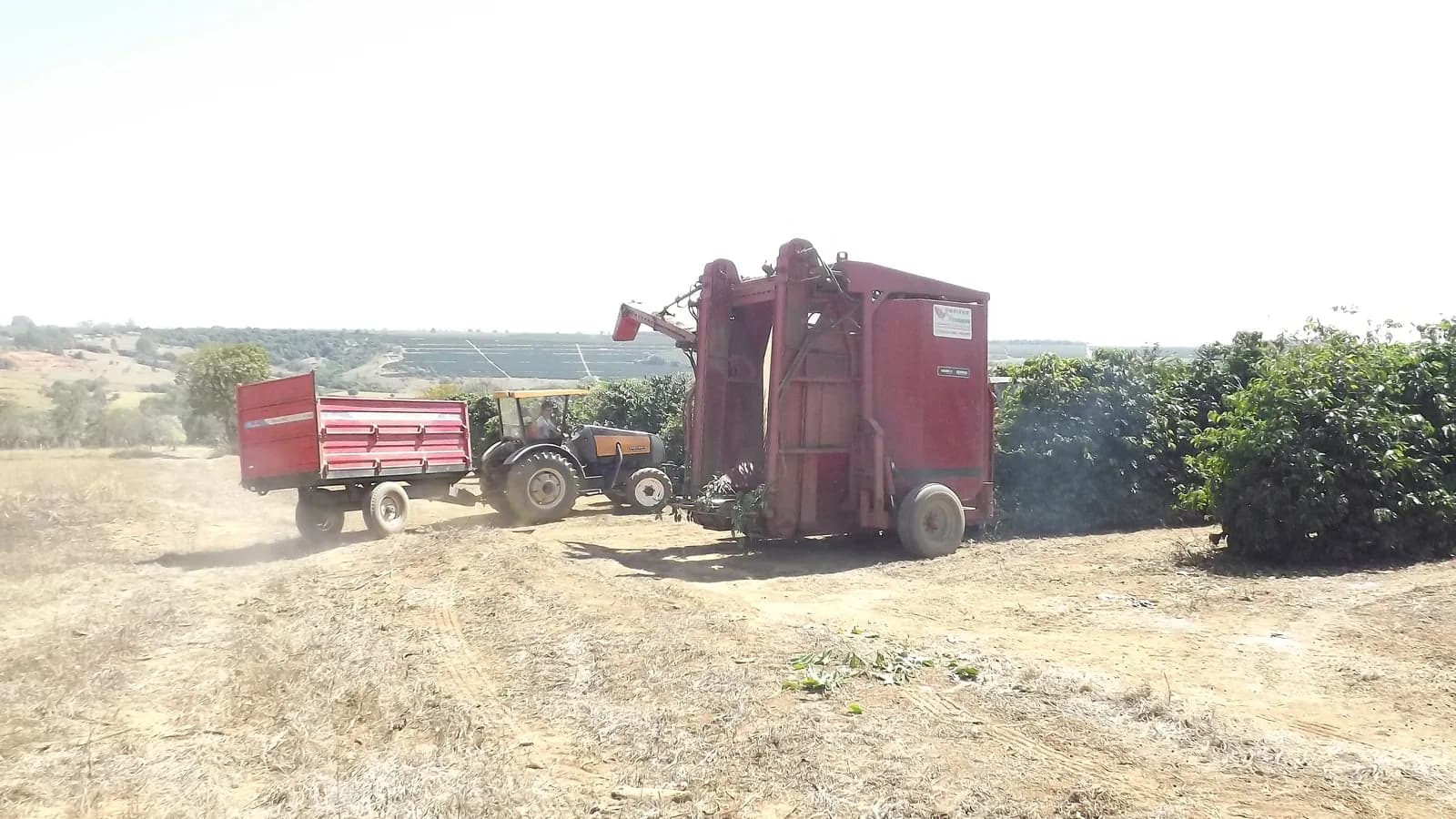 Trator e máquina colhedora em manobra no início da colheita mecanizada de café em Arapuá, Minas Gerais