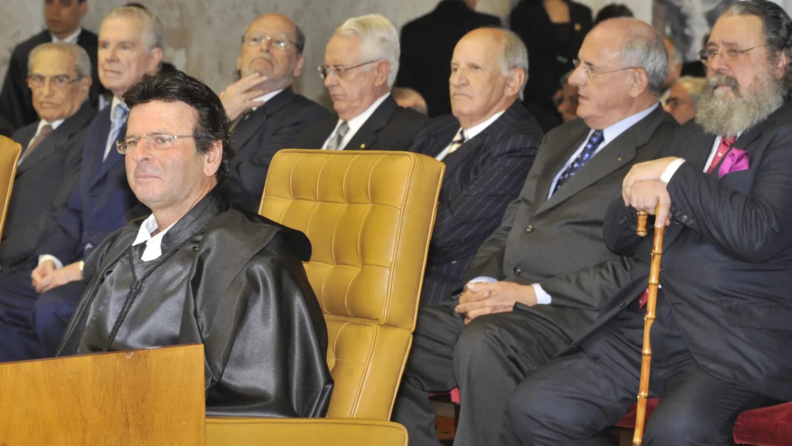 Luiz Fux, de toga preta, sentado em cadeira dourada durante cerimônia de posse no STF