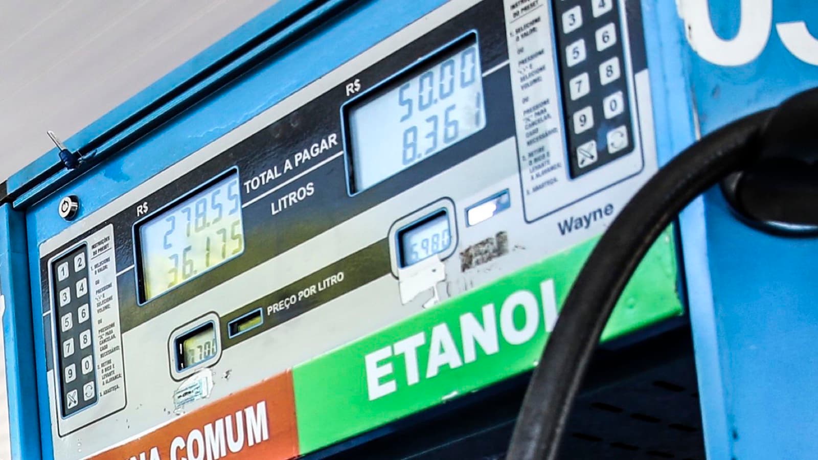 Bomba de combustível em posto, com os mostradores de preço e as faixas indicando gasolina comum e etanol