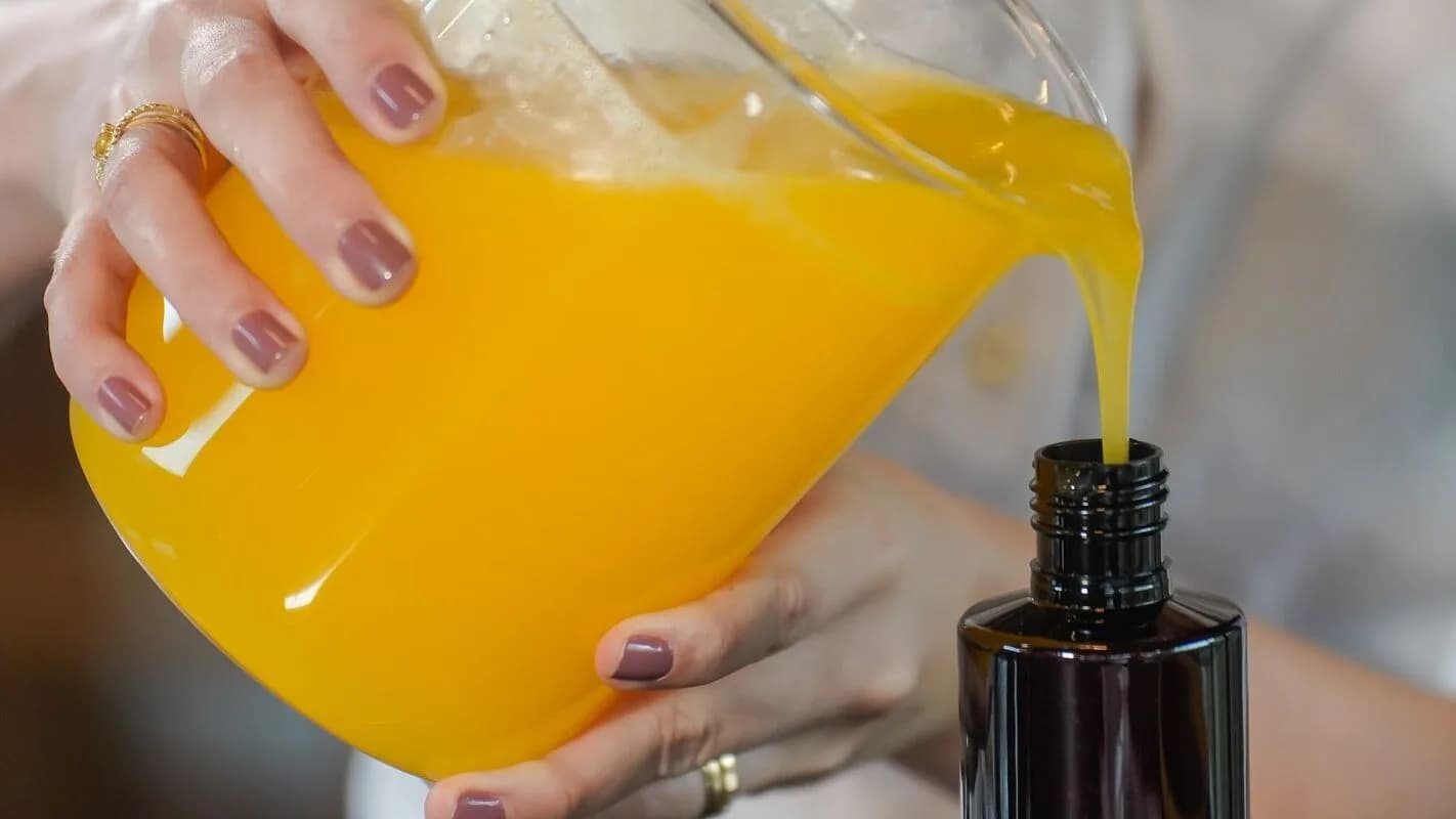 Produção artesanal de cosmético, com líquido sendo despejado em frasco