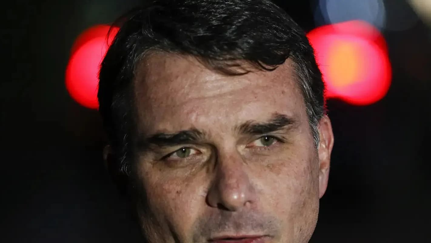 Retrato do senador Flávio Bolsonaro em ambiente noturno, com luzes desfocadas ao fundo