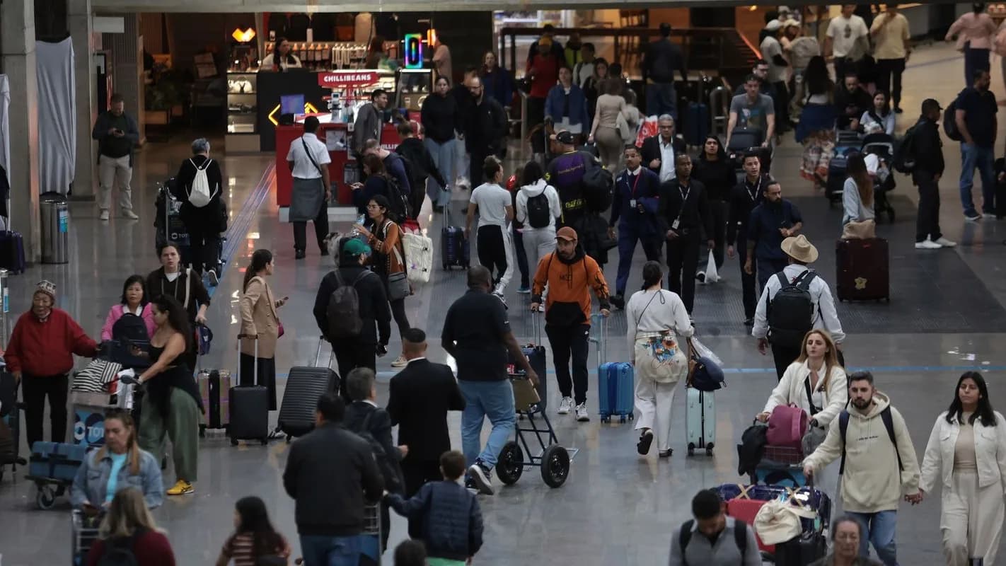 Passageiros com malas caminham pelo saguão do Aeroporto de Guarulhos em dia de grande movimento
