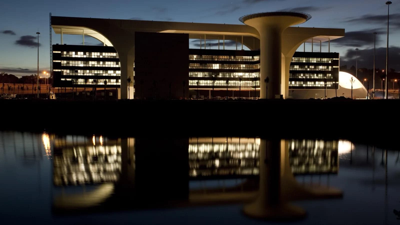 Cidade Administrativa de Minas Gerais, sede do governo estadual, iluminada ao entardecer e refletida no espelho d'água