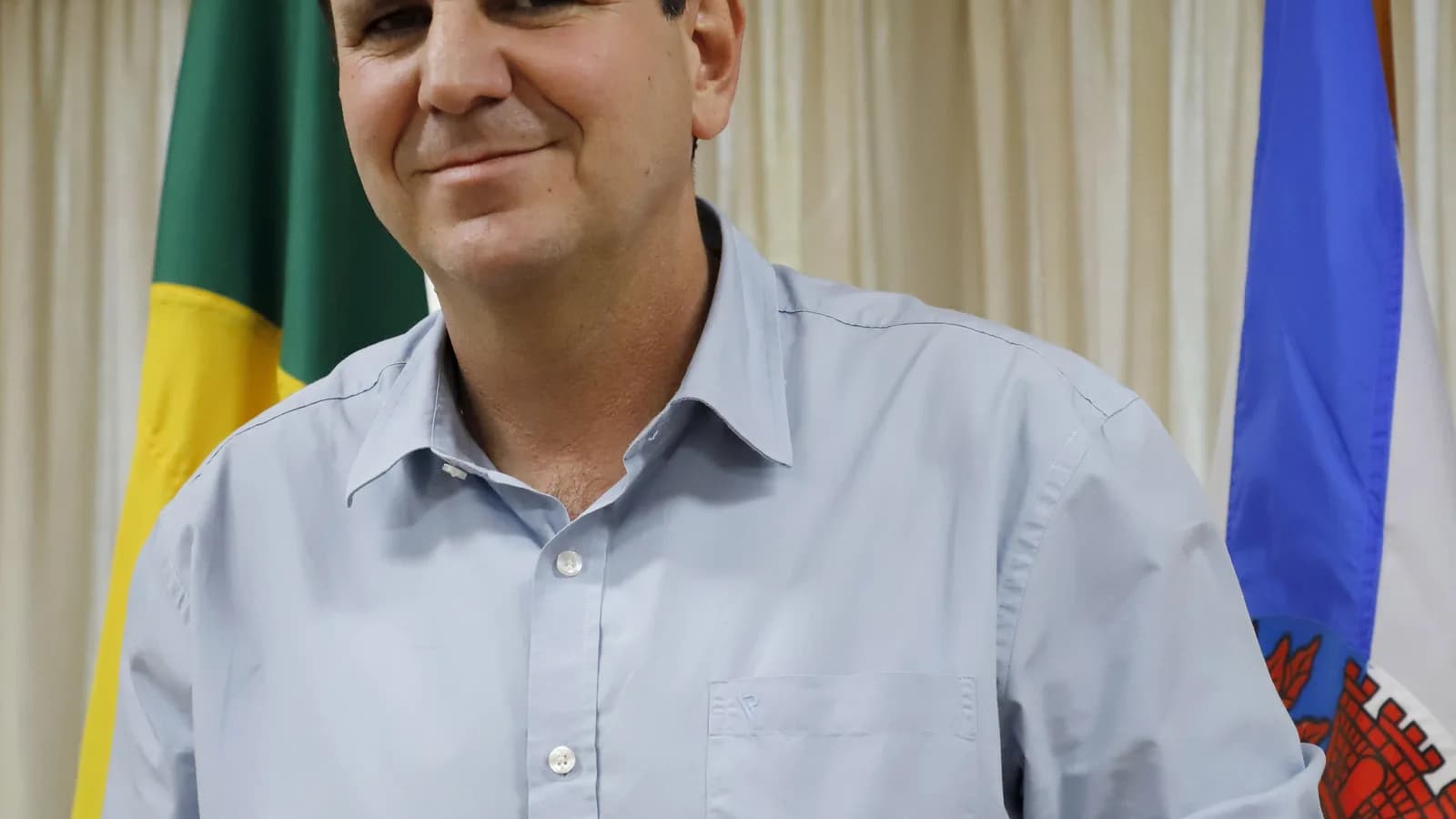Eduardo Paes, candidato ao governo do Rio de Janeiro, sorri em foto de arquivo com bandeiras ao fundo