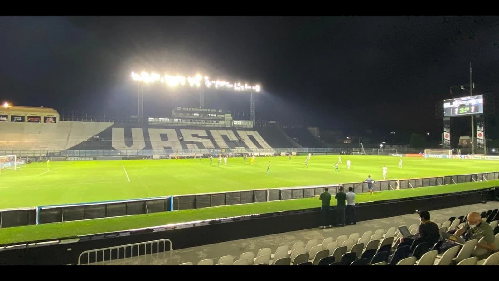 Estádio de São Januário à noite durante partida do Vasco, com o nome do clube nas arquibancadas