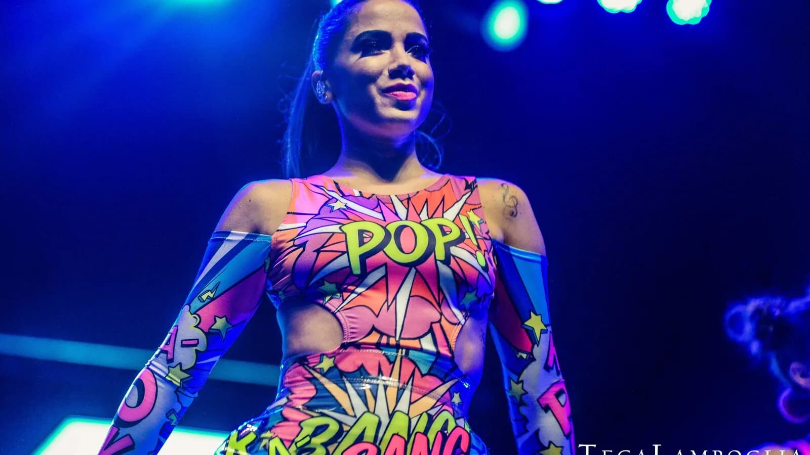 Anitta se apresentando em show, com figurino colorido em estilo pop art