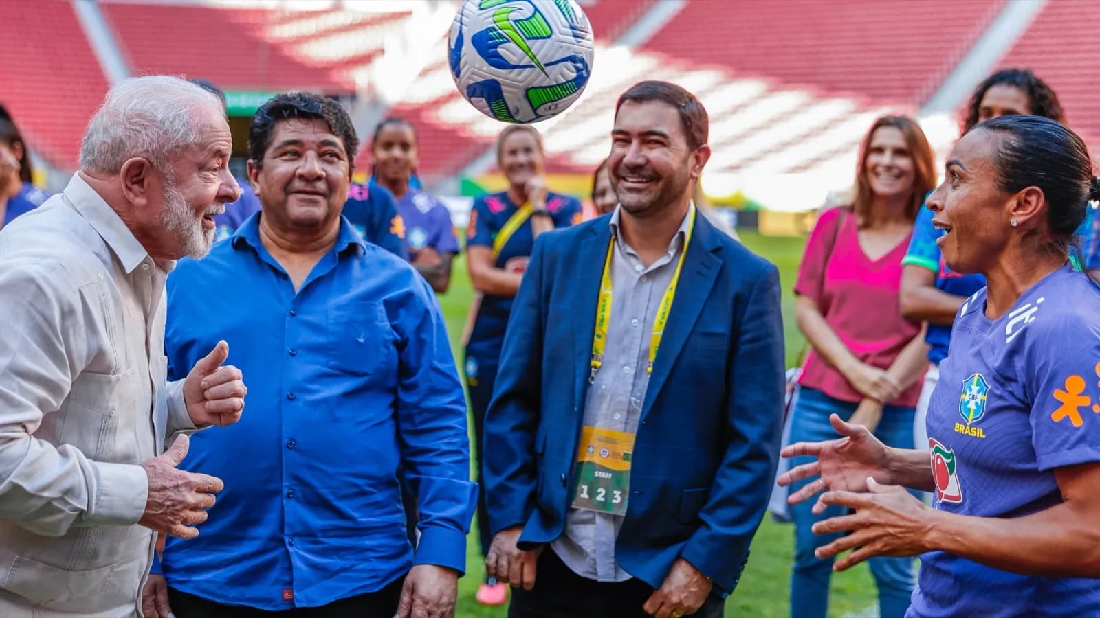 Marta e outras jogadoras da seleção brasileira feminina de futebol sorriem em campo durante encontro com autoridades