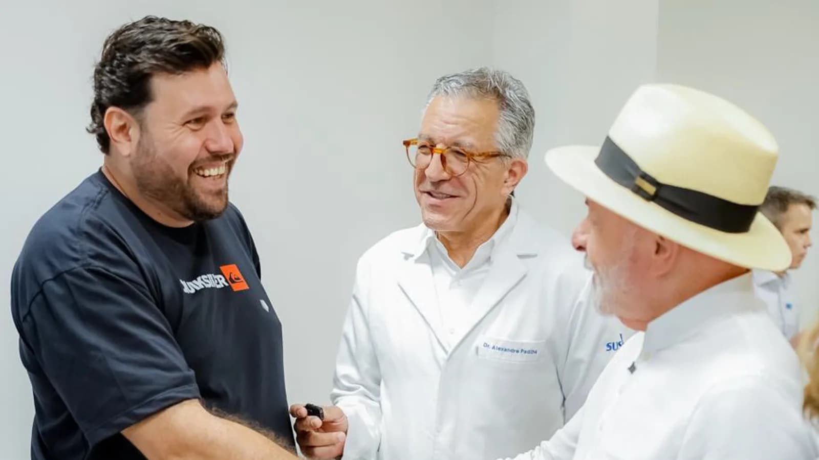 Paciente com prótese cumprimenta o ministro Padilha, com Lula ao lado, durante visita ao Hospital de Amor