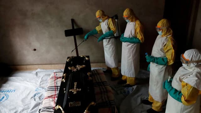Equipe de saúde paramentada com roupas de proteção realiza procedimento em resposta a surto de Ebola na África