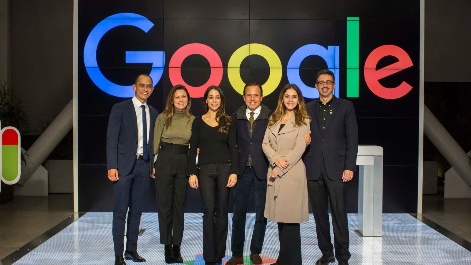 Grupo de pessoas em frente ao logotipo do Google em visita à sede da empresa