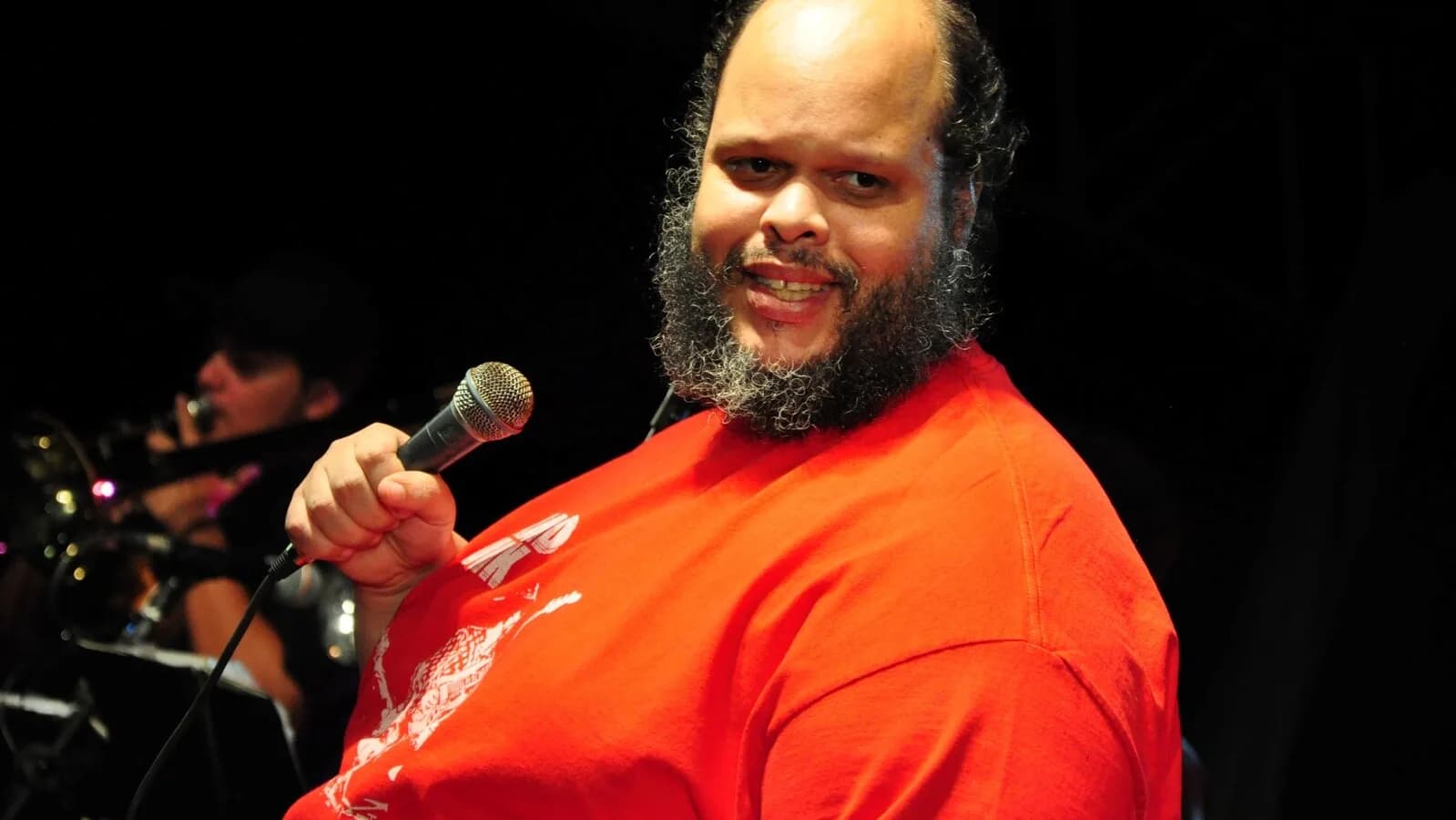 Ed Motta canta ao microfone durante apresentação ao vivo